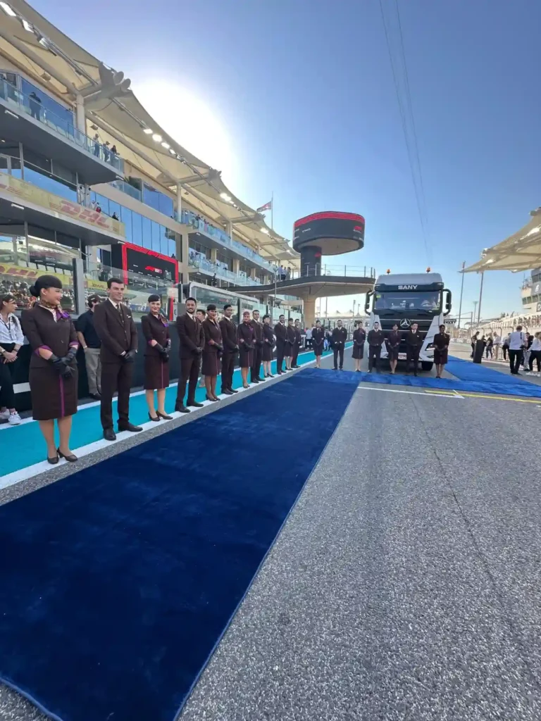 Členovia palubného personálu Etihad Airways v elegantných uniformách stoja v slávnostnom zástupe na pretekárskom okruhu F1